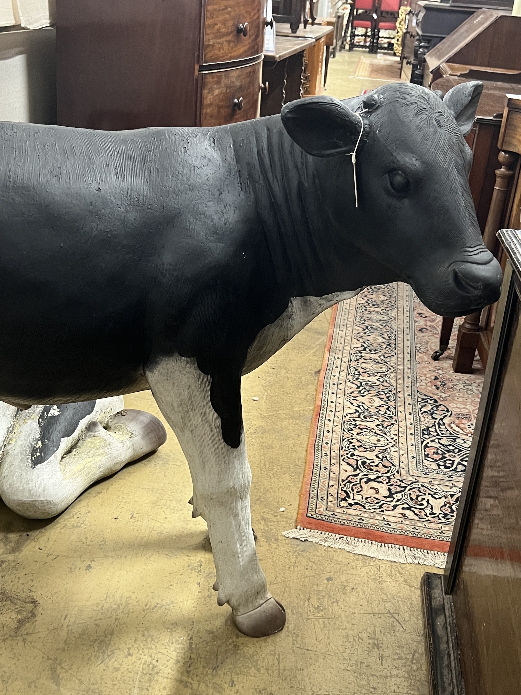 A life size composition Friesian calf garden ornament, length 118cm, height 96cm